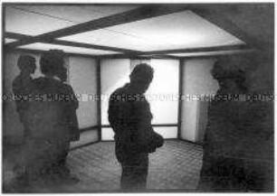 Vier Menschen betrachten eine Lichtinstallation in einem halbdunklen Raum (Altersgruppe 18-21)