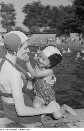 Porträt Renate Rössings in Badebekleidung mit einem kleinen Mädchen spielend im Freibad