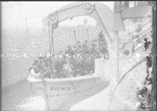 Besatzung mit Schwimmwesten und Fotografen in einem frei hängenden Beiboot des Hochseepassagierdampfers "Bremen"