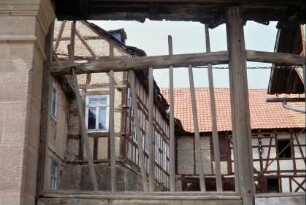 Blick durch ein stark beschädigtes Tor in einen Hof