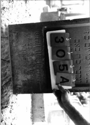 Grabstein 305 (Index: 99797857) Material: Sandstein, weiß Zustand: leicht verwittert Maße HxBxT: 100x45x12 cm Beschreibung: Stele, giebelartiger abgeflachter Abschluß, Sockel: Grabstein 305A