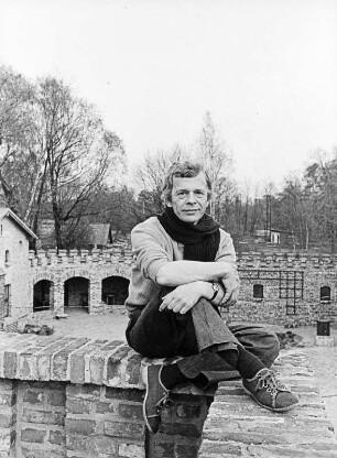 Der Schriftsteller Peter Hacks im Freien, aauf einer Mauer sitzend