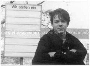 Junger Mann vor Schild mit der Aufschrift "Wir stellen ein" (Altersgruppe 14-17)