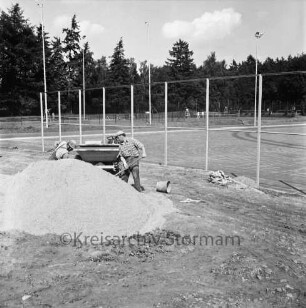 Oetjendorfer Landstraße / Waldweg: Turn- und Sportverein Hoisdorf: Sportzentrum: Anlage eines Sportplatzes: vorn links zwei Männer hinter Sandhaufen beim Schaufeln von Sand in eine kleine Baggerschaufel: dahinter Zaun: hinten Tennisplätze und Bäume
