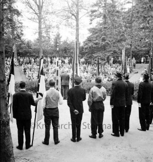 Tag der Deutschen Einheit: Feierstunde: Naturbühne: Bürgerpark: Bezirksverordnetenvorsteher Rudolf Michael [Rückenansicht] aus Berlin-Zehlendorf hält Ansprache am Rednerpult: hinten Zuhörer: im Vordergrund Jugend und Vertreter der Landsmannschaften mit Fahnen, 17. Juni 1963