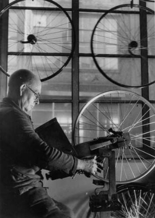 In einer Fahrradfabrik in Westfalen. Ein Arbeiter montiert und stellt Speichen an den Rädern ein. Aufgenommen 1949