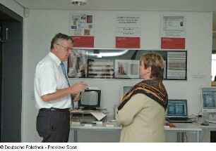 Restaurierungswerkstatt. Manuela Queitsch erläutert Herrn MR Joachim Linek, SMWK, die Präsentation "Langzeitarchivierung digitaler Medien als Beitrag zur Bestandserhaltung"