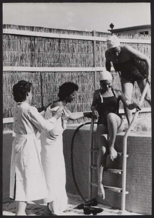 Zwei Frauen steigen aus dem Swimmingpool, zwei Andere befinden sich davor