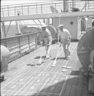 Zwei Passagiere beim Bord-Shuffle-Spiel an Deck des Hochseepassagierdampfers "Columbus"