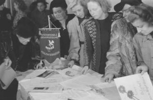 Verabschiedung einer Delegation des Demokratischen Frauenbundes Berlin mit Wilhelmine Schirmer-Pröscher, Elli Schmidt, Roberta Grupa und Eva Schmidt-Kolmer zum Kongress der Internationalen Demokratische Frauenföderation (IDFF) in Moskau : Frauen an einem Tisch mit Informationsmaterial der Internationalen Demokratischen Frauenföderation (IDFF)