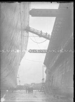 Hochseepassagierdampfer "Bremen" im Trockendock, gewaltige Seitenhöhe des Dampfers neben Anlegemauer, Querbrücken und winzig erscheinenden Personen, Bremerhaven