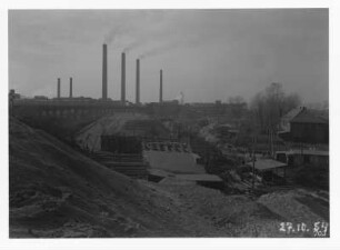 Industrie-Kraftwerk. Baustelle einer Eisenbahnbrücke (Grubenbahn über Werkgleis), im Hintergrund aufgeständerte alte Trasse der Grubenbahn und Werkanlagen mit Schornsteinen : Lauta (Niederlausitz). Industrie-Kraftwerk. Baustelle einer Eisenbahnbrücke (Grubenbahn über Werkgleis), im Hintergrund aufgeständerte alte Trasse der Grubenbahn und Werkanlagen mit Schornsteinen