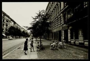 Straßenszene mit zwei Frauen und Kindern mit Kinderwagen