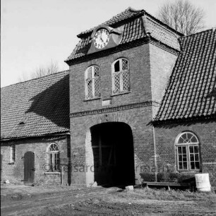 Gut Tangstedt: Torhaus mit Uhr und Durchfahrt: rechts an Wand Tonne