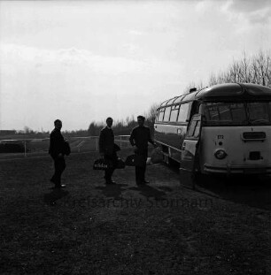 Kurparkstadion: vorn rechts Umkleidebus: links davor drei Sportler: hinten Sportplatz