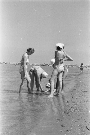Eforie. Vier junge Frauen spielen mit einem kleinen Kind im flachen Wasser am Strand am Schwarzen Meer