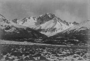 Berglandschaft : Blick über ein Feld auf verschneite Berge