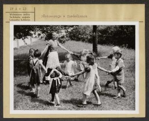 Kindergarten in Crostwitz. Kindergärtnerin in sorbischer katholischer Alltagstracht. : Pěstowarnja w Chrósćicach. Kubłarka w serbskej katolskej wšědnej drasće.