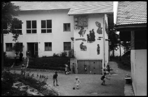 Imst: SOS Kinderdorf, Wandbild an der Außenseite der Schule [mit spielenden Kindern im Vordergrund]