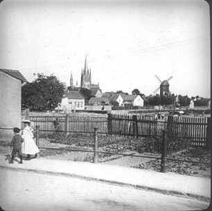 Werder (Havel). Stadtansicht mit Pfarrkirche Heilig-Geist und Bockwindmühle. Blick über einen Gemüsegarten