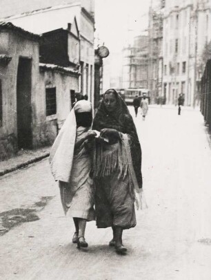Sarajevo (Bosnien und Herzegowina). Straßenszene. Links eine verschleierte Frau, rechts eine Frau im Hosenrock. Im Hintergrund eine Straßenbahn