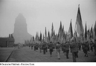 Jugendliche tragen Deutschlandflaggen während eines Umzugs zum Gedenken an die Völkerschlacht, im Hintergrund das Völkerschlachtdenkmal