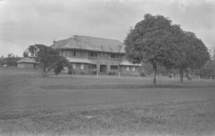 Haus im Kolonialstil : Blick über eine Wiese auf ein Anwesen im Kolonialstil