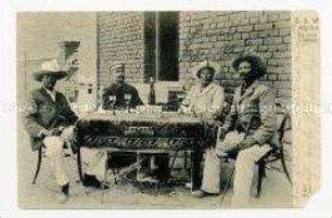 Afrikaner und Deutscher an einem Tisch, mit Wein und Zigarren