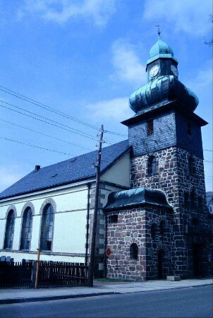 Kirche mit Turm, Uhr und Wetterfahne; neben dem Turm sogenannte Torhäuser