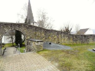 Ansicht von Norden über Bergseite (mit erweitertem Freidhof 20 Jh)-Kirchhofmauer mit neuzeitlichem Torbogen im Verlauf nach Westen (Wehrgang mit Steinbrüstung im 18 Jh abgetragen)