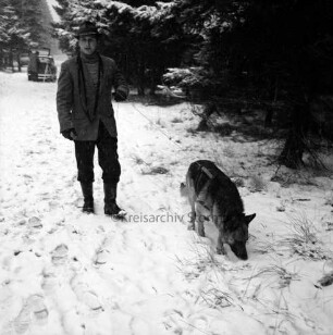 Polizei: Mord an der Hamburger Küchenhilfe Edeltraut Harloff am 26. November 1965: Oher Tannen: Leichenfundort: Spurensuche mit Suchhund: Tischler Peter Lehmkuhl mit seinem Schäferhund "Bingo" auf Weg: hinten links Pkw mit geöffneter Heckklappe: davor Polizeibeamter mit Fotostativ: hinten Tannen: Winter