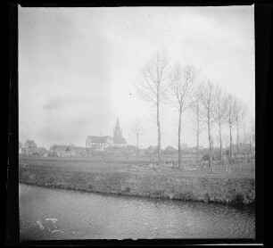 Comines-Warneton (Belgien): Kirche [Saint-Chrysole], im Vordergrund Kanal und Feld (Distanzaufnahme) ("Französisch- und Belgisch-Comines mit Kanal")