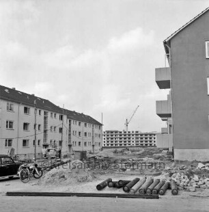 Klosterbergen: Bogenstraße: rechts und links dreigeschossige Wohnblocks vor Fertigstellung: in der Mitte Reste von Baumaterial auf unbefestigtem Gelände: vorn rechts Gasflaschen: links Pkw und Fahrrad: dahinter Lieferwagen mit zwei Personen vor Eingang: hinten Mitte achtgeschossiges Punkthaus im Bau: davor Baukran