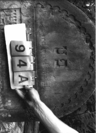 Grabstein 94 (Index: 100110777) Material: Sandstein Zustand: leicht verwittert mit einzelnen Abschieferungen, geringer Textverlust Maße HxBxT: 110x69x12 cm Beschreibung: Stele, Rundbogenabschluß mit Rundbogenfries, Schriftfelder eingetieft Symbolik: 4 Blüten: Grabstein 94A