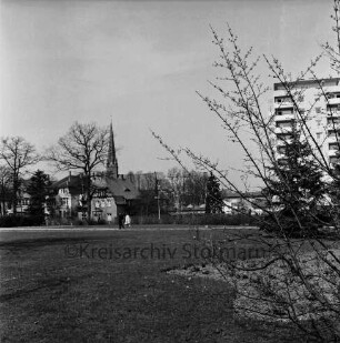 Kurpark: vorn Grünfläche: dahinter Kurparkallee mit Stadtvillen und Paar: rechts Hochhaus "Liebe": hinten links Peter-Paul-Kirche