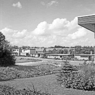 Wohngebiet zwischen Kolberg-Körliner Straße, Danziger Straße und Memeler Straße: Blick von Ehmkenberg II: im Vordergrund Rasenfläche mit Sträuchern: links Baum: dahinter Pkws: rechts Dachkante