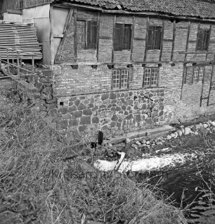 Drahtmühle: Restaurierung: vorn rechts Mühlenbach: links Sträucher: dahinter Stapel mit Brettern