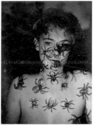 Junge Frau, auf deren nacktem Oberkörper und Gesicht große Spinnen projiziert werden (Altersgruppe 18-21)