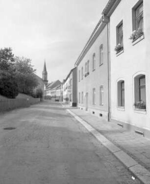Schöneck. Forststraße. Straßenansicht mit Wohnhäusern. Blick gegen Kirchturm