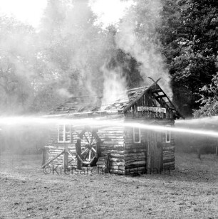 Kupfermühle: Amtsfeuerwehrfest: Löschen der "Kupfermühle Anno 1500": brennendes Holzhäuschen mit Wasserstrahlen: dahinter Wald