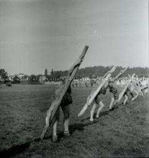 Arbeitsmänner des Reichsarbeitsdienstes beim Krafttraining mit Holzstämmen