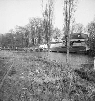 Trave: vorn Baumreihe am Ufer: hinten rechts alte Badeanstalt: hinten links Holzbrücke: dahinter Bäume des Bürgerparks