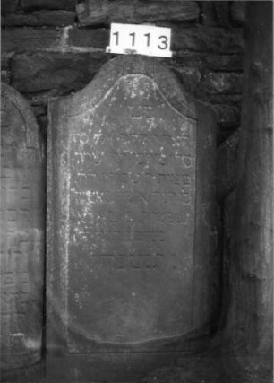 Grabstein 1113 (Index: 99630616) Material: Sandstein Zustand: verwittert Maße HxBxT: 121x61x12 cm Beschreibung: Stele mit Konvexbogenabschluß, Schriftfeld eingetieft: Grabstein 1113
