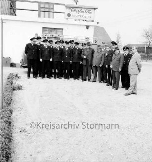 Sühlen: Freiwillige Feuerwehr: Übergabe des neuen Löschfahrzeugs: Gruppenbild mit Wehrführer Hans Rieken junior, Kreisbrandmeister Hinrich Harms, Amtswehrführer Justus Degenhardt, Kreisfachwart Heinrich Sager, Bürgermeister Hans Rieken senior und Gemeindevertretern: im Hintergrund der Gasthof "Zur Scharfen Ecke"