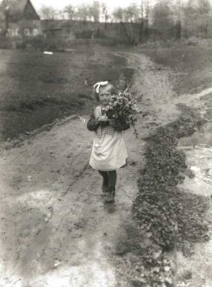 Mädchen mit Blumenstrauß auf einem Feldweg