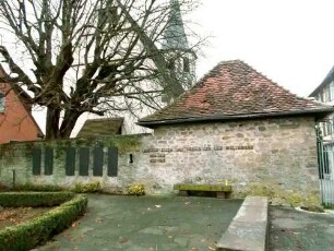 Kirche-Ansicht von Westen über Feldseite mit Kirchhofmauer (erhaltene Schlüsselloch-Schießscharte in Brusthöhe) sowie Bahrhaus im Südwesten-Wehrgang mit Steinbrüstung im 19 Jh abgetragen