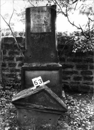 Grabstein 53 (Index: 99804392) Material: Sandstein Zustand: Giebel gebrochen, liegt vor dem Stein, große Platte fehlt ?? (Löcher) Maße HxBxT: 204x60x31 cm Beschreibung: Stele, getreppter Sockel, Giebel, rechteckige Schrifttafel Symbolik: achtzackiger Stern: Grabstein 53