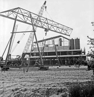 Hartsteinwerk: Rohbau: links Kranwagen mit Ausleger: daran Brückenteil einer Laufkatze: vorn links und hinten Mitte Ständer: hinten Werkhalle im Aufbau