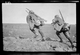 Übungsgelände I bei Mouzon (Dep. Ardennes, Frankreich): 2 Soldaten mit Stahlhelm und voller Ausrüstung beim Herausstürmen aus einem Graben (Rückansicht, Nahaufnahme) ("Infanterie im Vorgehen")