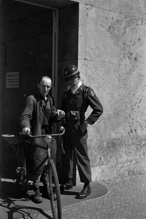 Berlin-Dahlem. Portrait eines Soldaten der US-Army und eines Arbeiters mit Fahrrad vor dem Eingang zum Hauptgebäude der US Army in Berlin-Dahlem